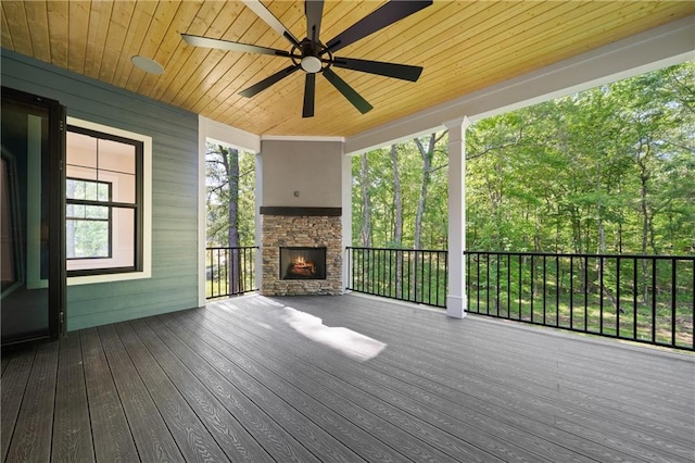 deck featuring an outdoor stone fireplace and ceiling fan