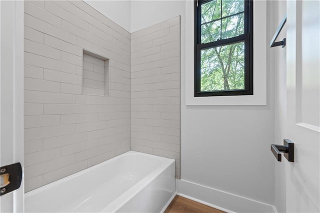 full bathroom with baseboards, bathing tub / shower combination, and wood finished floors