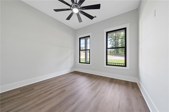 empty room featuring dark wood-style floors, baseboards, and a ceiling fan