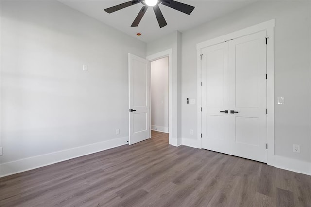 unfurnished bedroom with wood finished floors, a closet, baseboards, and ceiling fan