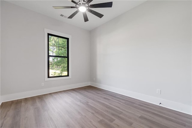 unfurnished room with wood finished floors, a ceiling fan, baseboards, and vaulted ceiling
