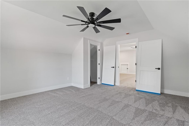 unfurnished bedroom featuring lofted ceiling, carpet flooring, ceiling fan, and baseboards
