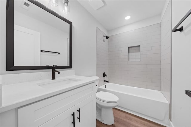 bathroom featuring wood finished floors, toilet, vanity, shower / bathtub combination, and recessed lighting