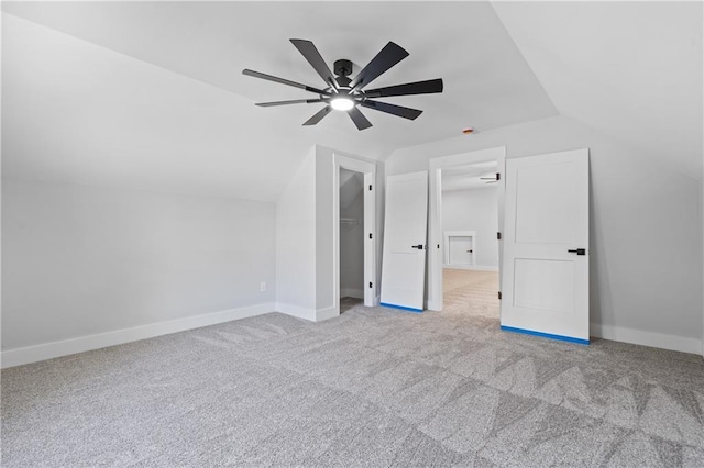 unfurnished bedroom with vaulted ceiling, carpet floors, ceiling fan, a spacious closet, and baseboards