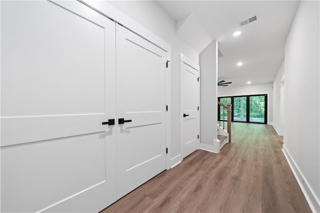 hallway featuring baseboards, wood finished floors, recessed lighting, and stairway