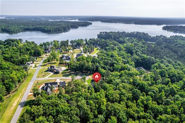 aerial view of property and surrounding area featuring a nearby body of water and a heavily wooded area