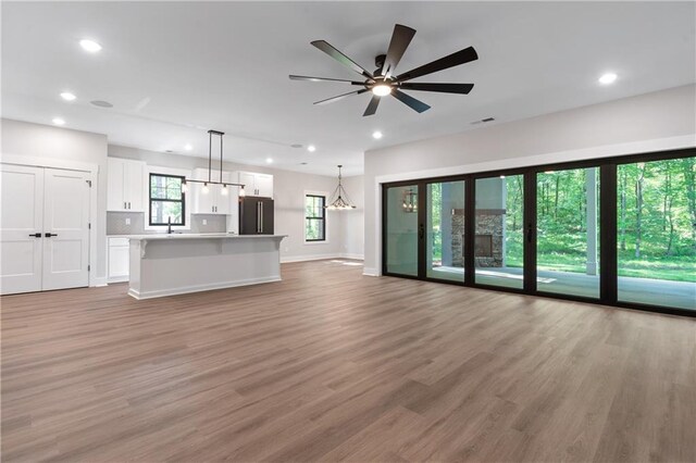 unfurnished living room featuring light wood-style floors, recessed lighting, a sink, baseboards, and ceiling fan