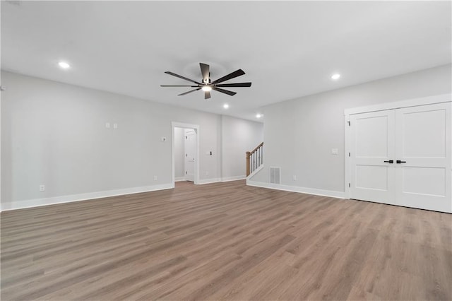 unfurnished living room featuring ceiling fan, stairway, recessed lighting, light wood-type flooring, and baseboards