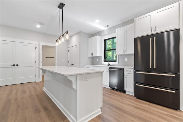 kitchen with black fridge, stainless steel dishwasher, light countertops, white cabinetry, and recessed lighting