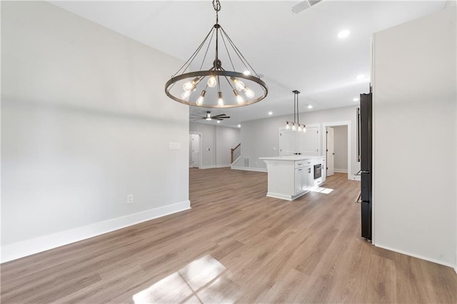 spare room with a chandelier, recessed lighting, baseboards, light wood-style flooring, and stairway