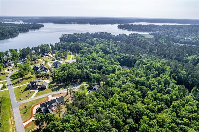 drone / aerial view of a nearby body of water and a forest
