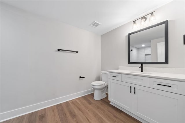full bath with wood finished floors, vanity, baseboards, toilet, and a shower
