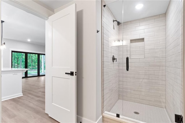 bathroom with a stall shower, wood finished floors, recessed lighting, and baseboards
