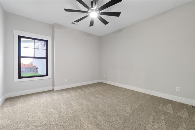 empty room featuring carpet, baseboards, and a ceiling fan