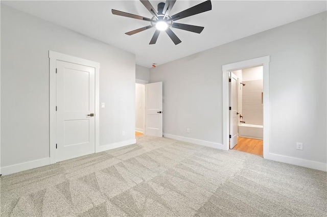 unfurnished bedroom with carpet flooring, baseboards, ensuite bath, and a ceiling fan