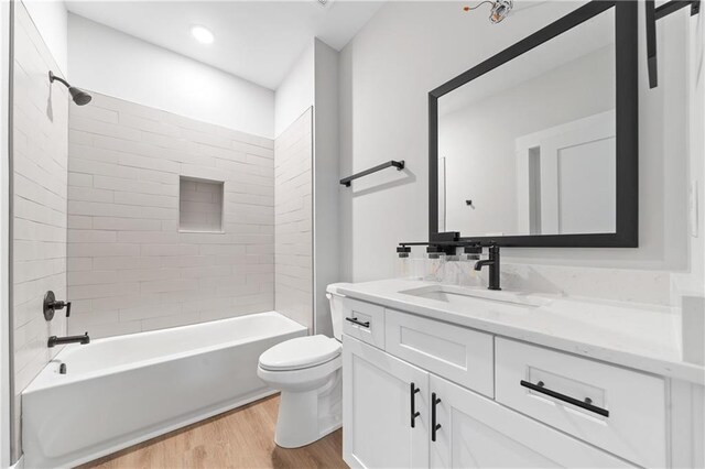 full bath with wood finished floors, toilet, vanity, and bathtub / shower combination