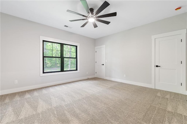 carpeted spare room with a ceiling fan and baseboards