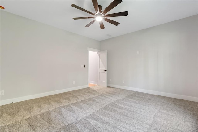 spare room with light colored carpet, a ceiling fan, and baseboards