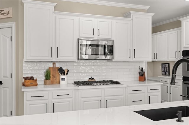 kitchen with stainless steel appliances, white cabinetry, light countertops, backsplash, and crown molding