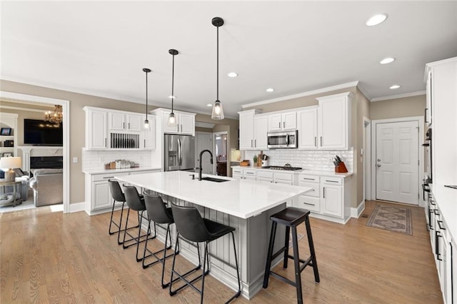 kitchen with appliances with stainless steel finishes, an island with sink, a kitchen bar, and a sink