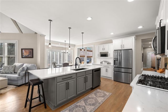 kitchen with appliances with stainless steel finishes, white cabinets, a sink, and open floor plan