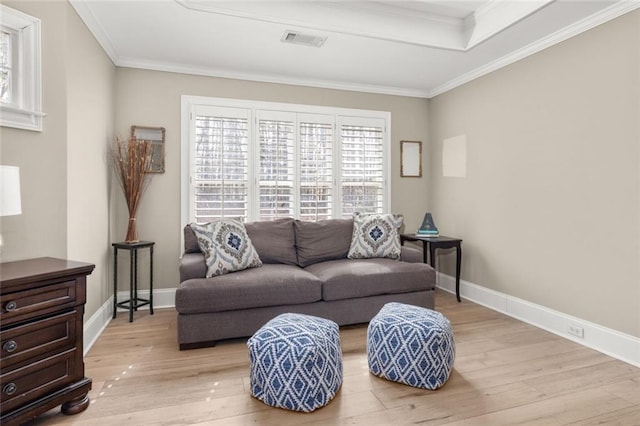 living room with baseboards, light wood-type flooring, visible vents, and crown molding