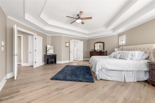 bedroom with light wood finished floors, baseboards, a raised ceiling, and ornamental molding