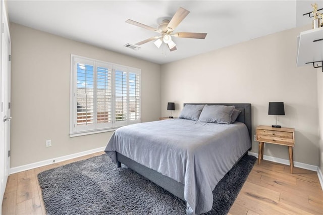 bedroom featuring light wood-style flooring, a ceiling fan, visible vents, and baseboards