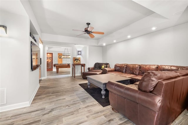 living area with baseboards, a ceiling fan, light wood-style flooring, a tray ceiling, and recessed lighting