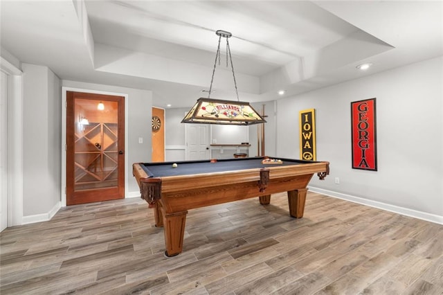 rec room featuring a tray ceiling, baseboards, and wood finished floors