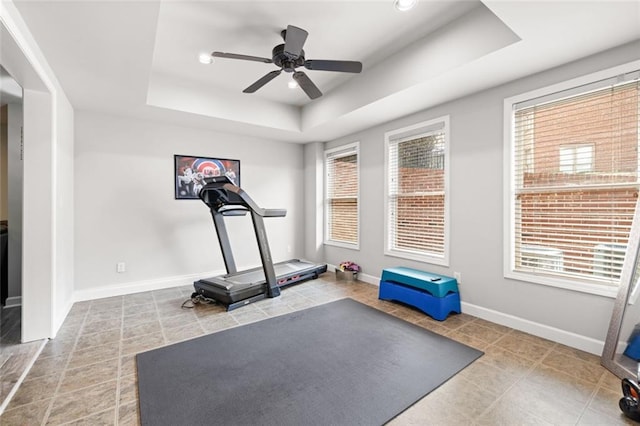 exercise room with baseboards, ceiling fan, tile patterned flooring, a tray ceiling, and recessed lighting