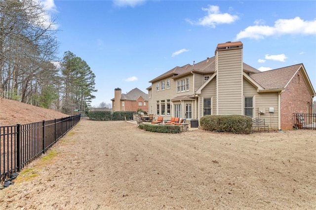 rear view of property with a chimney, a patio area, and a fenced backyard