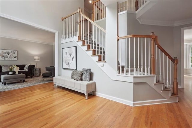 stairs featuring hardwood / wood-style flooring, a towering ceiling, and ornamental molding