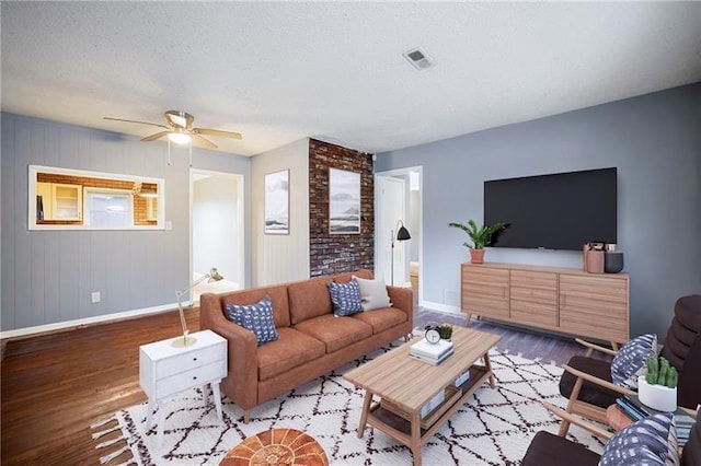 living room featuring ceiling fan, wood-type flooring, and a textured ceiling