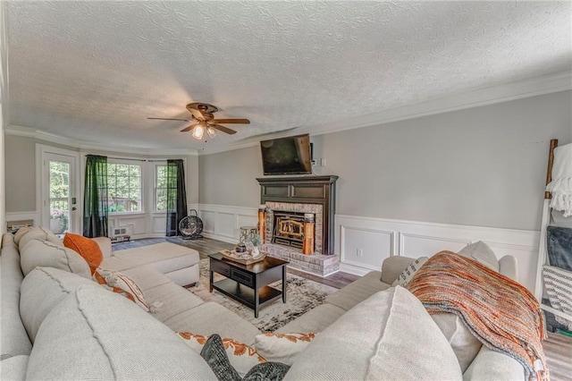 323 Schoolhouse Rd, Rockmart, GA 30153 - living room with a ceiling fan, a brick fireplace, ornamental molding, a textured ceiling, and wainscoting