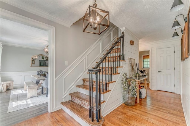 323 Schoolhouse Rd, Rockmart, GA 30153 - staircase featuring a chandelier, wood finished floors, a textured ceiling, ornamental molding, and a decorative wall