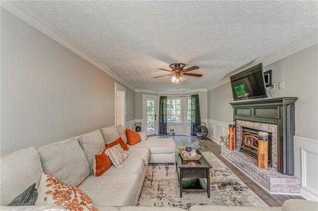 323 Schoolhouse Rd, Rockmart, GA 30153 - living area featuring a fireplace, ceiling fan, wood finished floors, crown molding, and a textured ceiling
