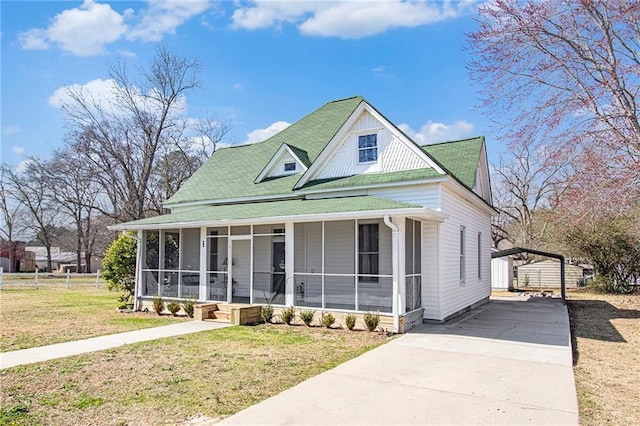 view of front of property featuring concrete driveway, a front lawn, a porch, and a sunroom