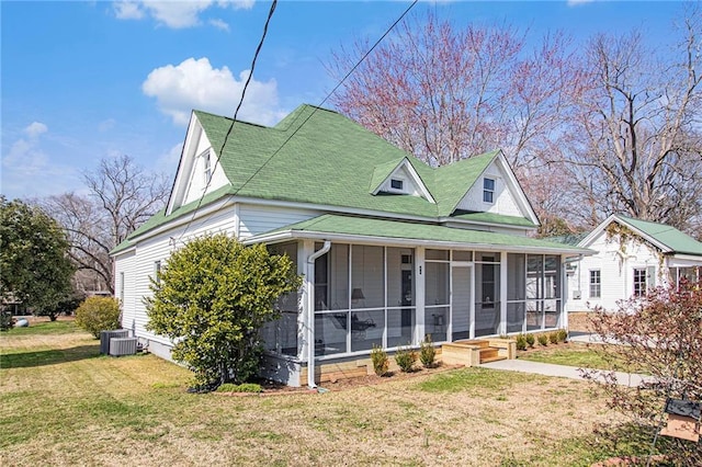 farmhouse inspired home with a front yard, a sunroom, and central AC unit