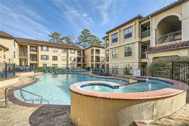 view of swimming pool featuring pool water feature, a hot tub, and a patio area