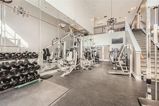 exercise room featuring an inviting chandelier and a high ceiling