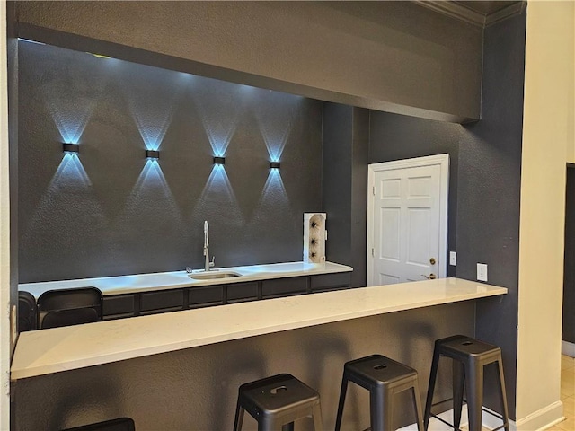 kitchen featuring sink, light tile patterned floors, and a kitchen bar