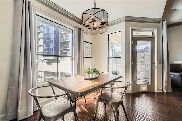 dining area featuring an inviting chandelier, ornamental molding, and dark hardwood / wood-style floors