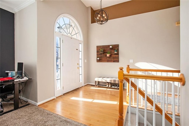 entryway with crown molding, hardwood / wood-style flooring, and a notable chandelier