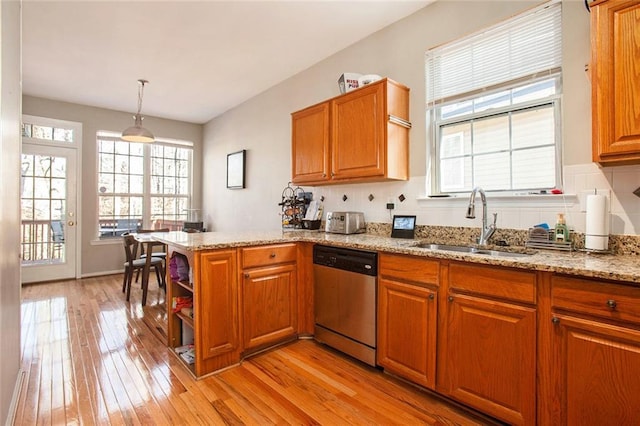 kitchen with sink, dishwasher, light hardwood / wood-style flooring, kitchen peninsula, and hanging light fixtures