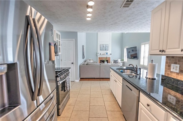 1510 Ridgemill Ter, Dacula, GA 30019 - kitchen with appliances with stainless steel finishes, a sink, a brick fireplace, decorative backsplash, and dark stone countertops