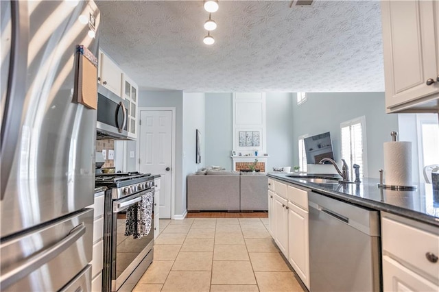 1510 Ridgemill Ter, Dacula, GA 30019 - kitchen featuring appliances with stainless steel finishes, a sink, white cabinets, open floor plan, and a textured ceiling