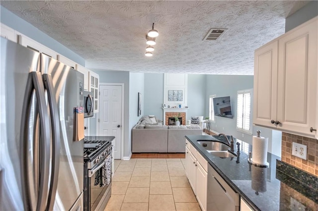 1510 Ridgemill Ter, Dacula, GA 30019 - kitchen with stainless steel appliances, a sink, a brick fireplace, open floor plan, and light tile patterned flooring