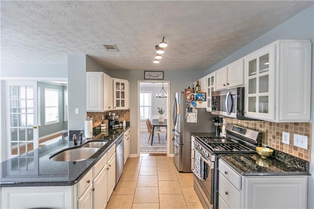 1510 Ridgemill Ter, Dacula, GA 30019 - kitchen featuring appliances with stainless steel finishes, a sink, decorative backsplash, white cabinetry, and a textured ceiling