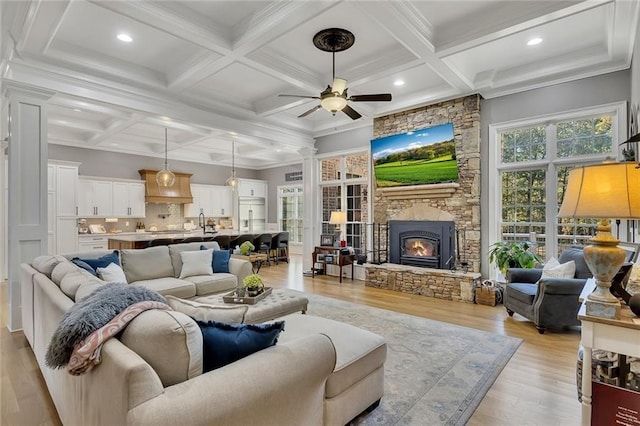 living room with a fireplace, ornate columns, light wood-type flooring, ceiling fan, and beam ceiling